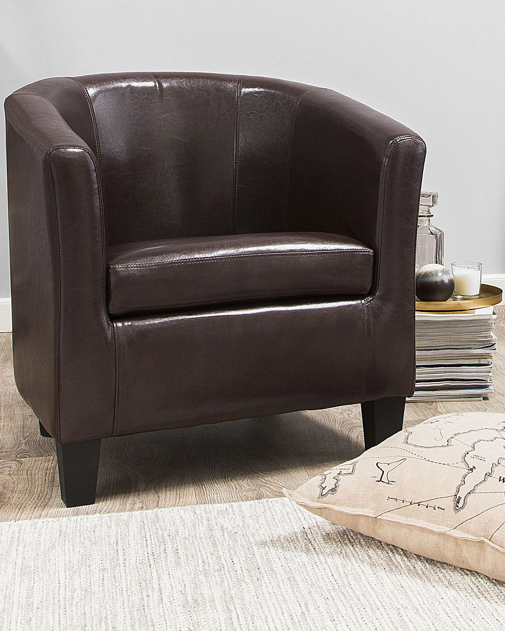 Brown leather armchair in a room with a decorative pillow and books.