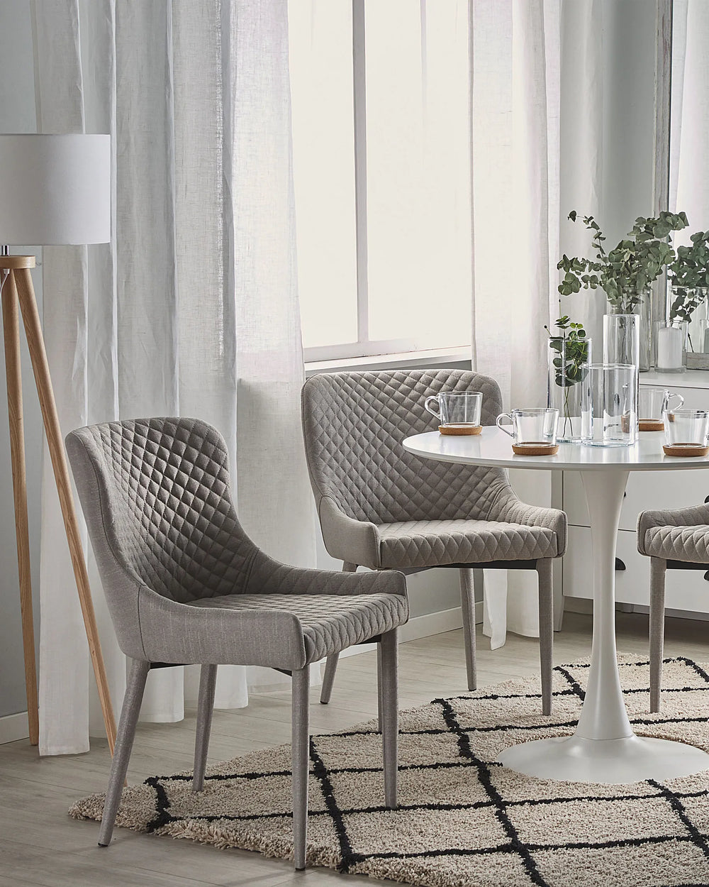 Light Grey quilted dining chairs paired with a glass-top table in a stylish modern dining room.