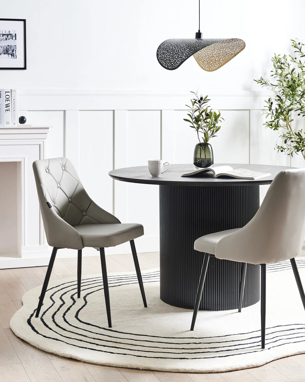 Stylish dining space featuring the chair’s soft beige upholstery and quilted backrest, paired with a black pedestal table to create a bright, modern, and inviting atmosphere.