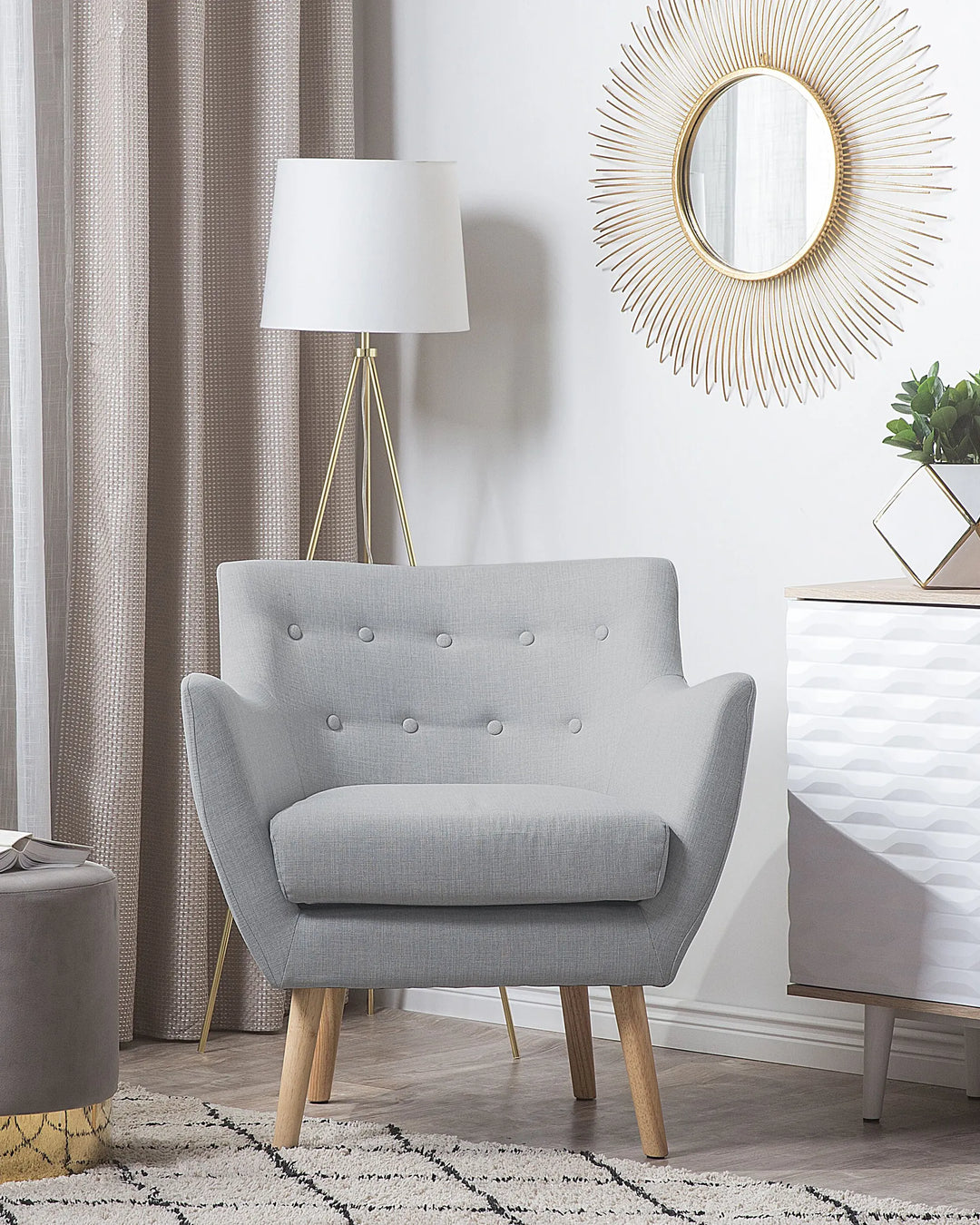 Gray armchair in a living room setting with a lamp, mirror, and decor items.