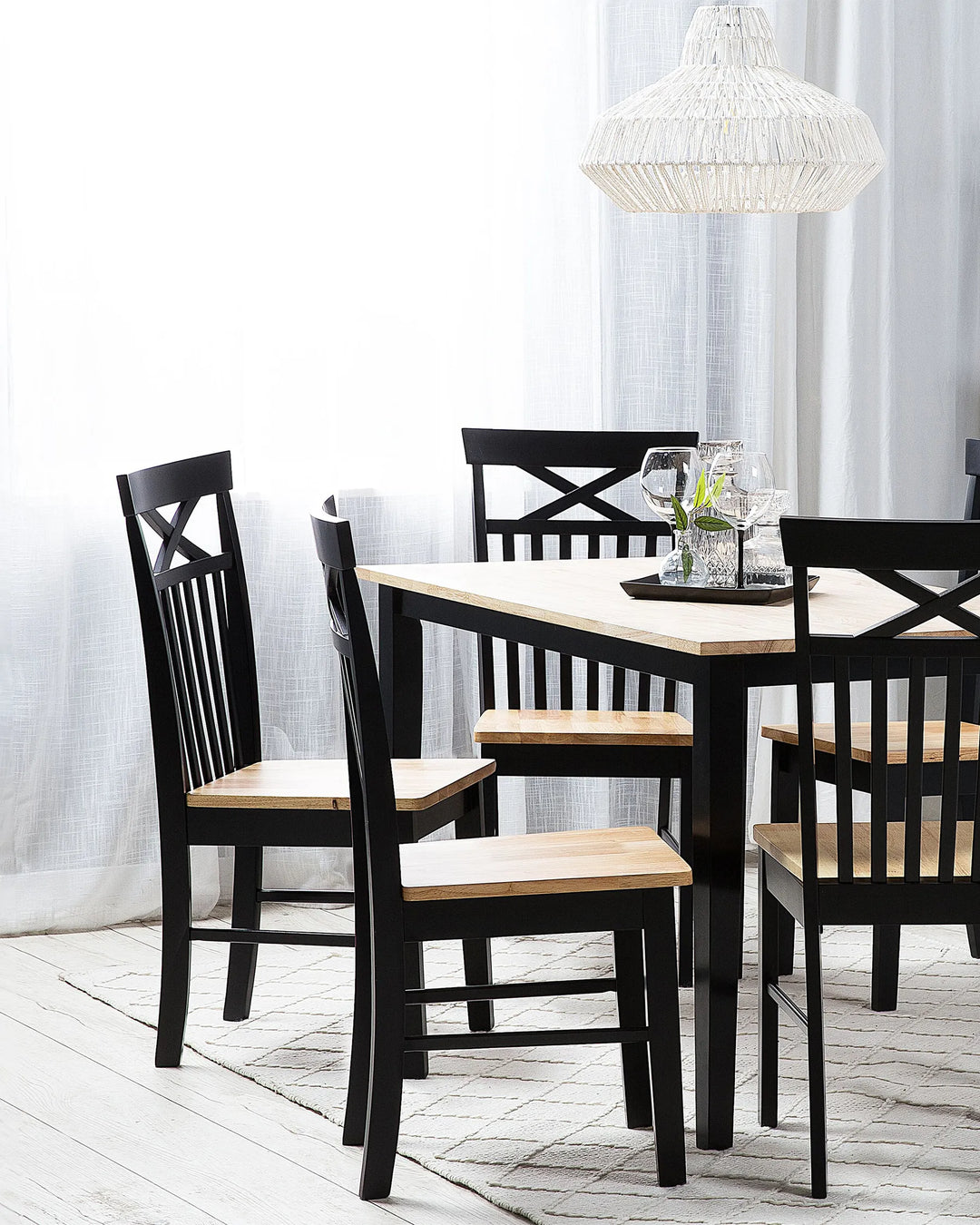 Traditional farmhouse-style dining chairs styled around a matching two-tone dining table in a bright, airy dining room with soft natural light, woven pendant lighting, neutral textiles, and a cozy modern rustic aesthetic.