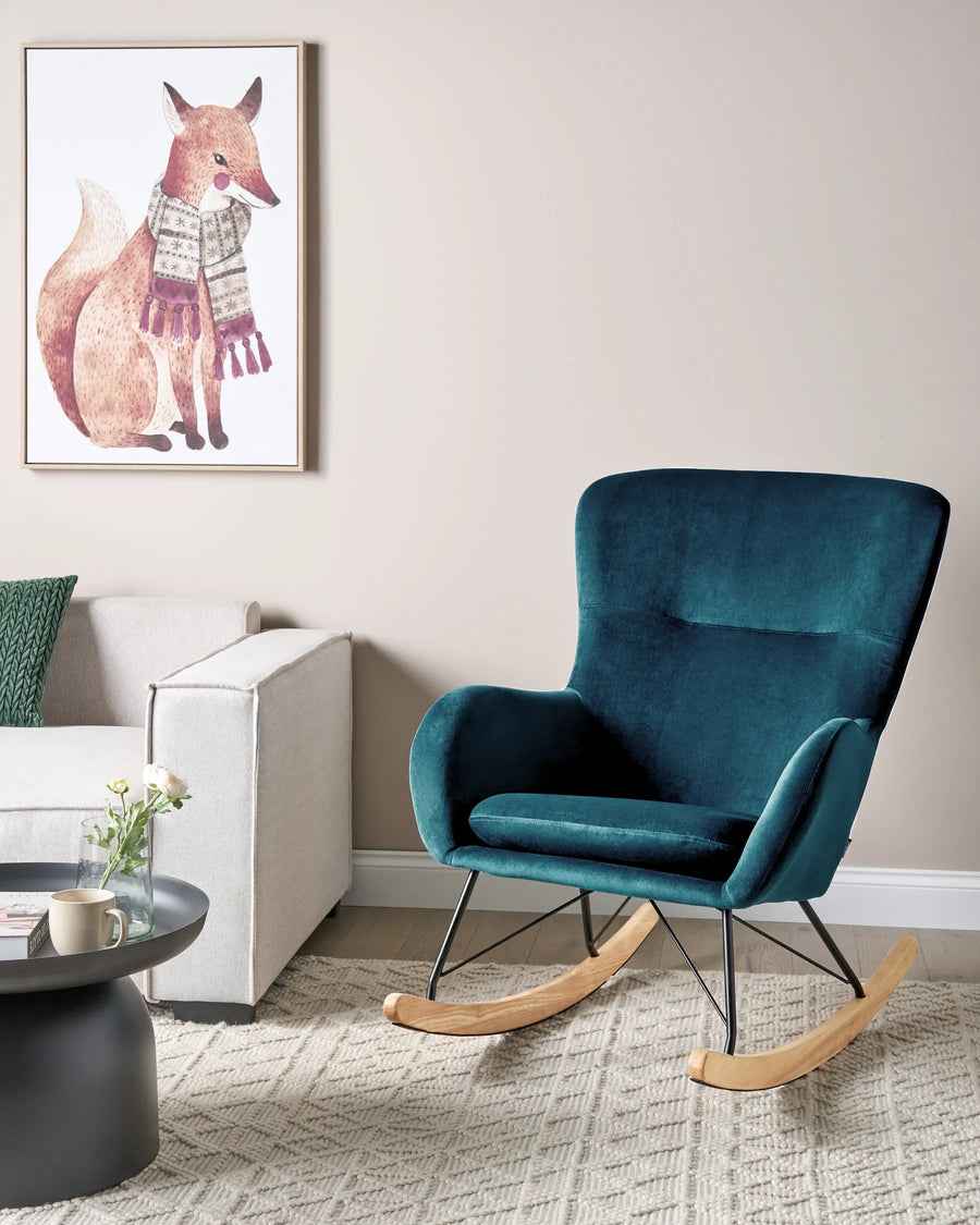 Blue rocking chair in a living room with a framed picture of a fox wearing a scarf on the wall.