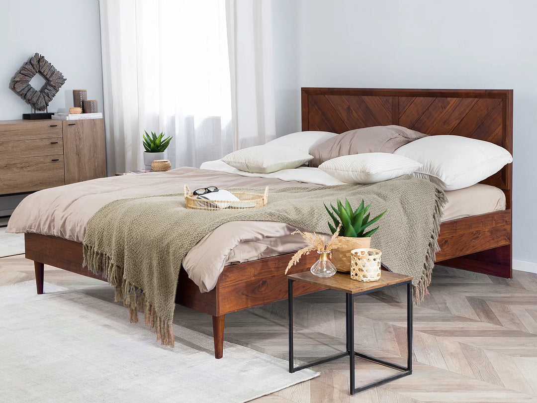 Dark wood bed frame with slatted headboard and white bedding, sunlit modern bedroom with large window, warm natural light and cozy minimalist style.