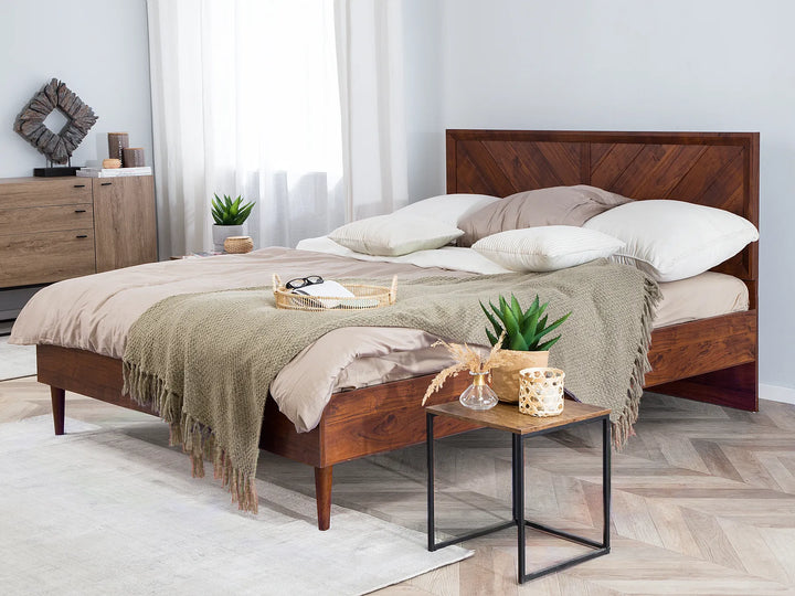 Dark wood bed frame with slatted headboard and white bedding, sunlit modern bedroom with large window, warm natural light and cozy minimalist style.