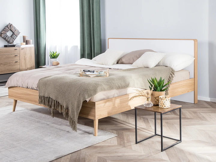 Light brown wooden bed frame with a clean design, placed in a modern bedroom with neutral colors and simple decor in the background.