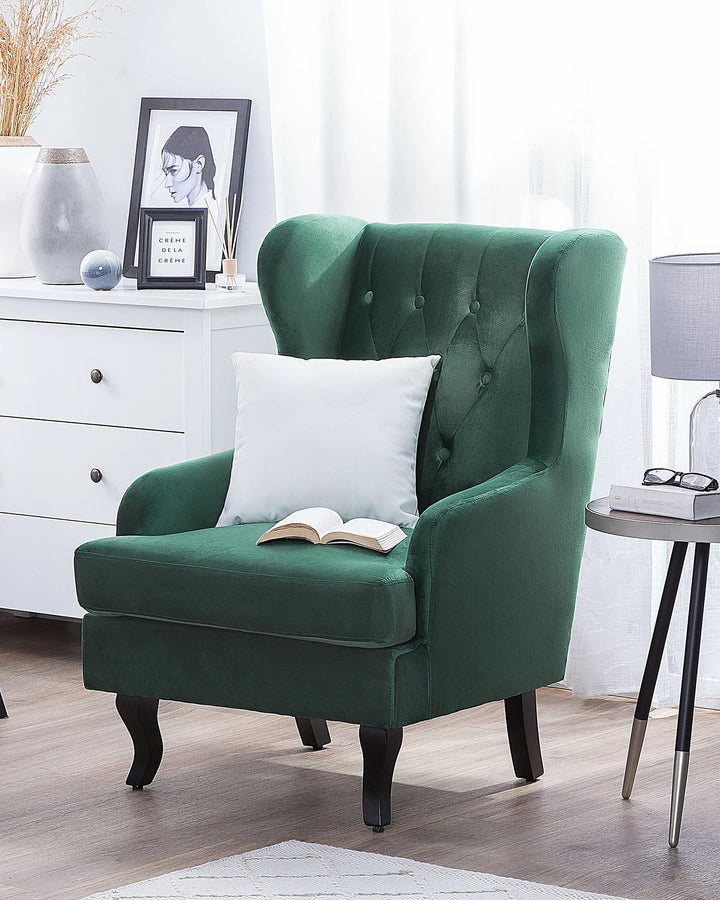 Green armchair with a white pillow and open book in a room setting.