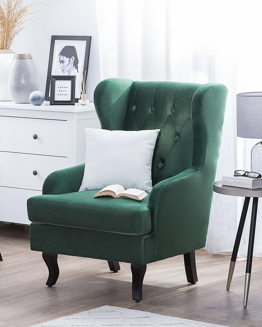 Green armchair with a white pillow and open book in a room setting.