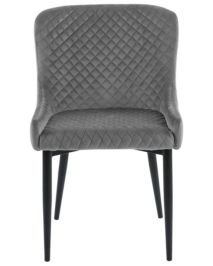 Grey velvet dining chair with diamond quilting, curved armrests, and black metal legs.