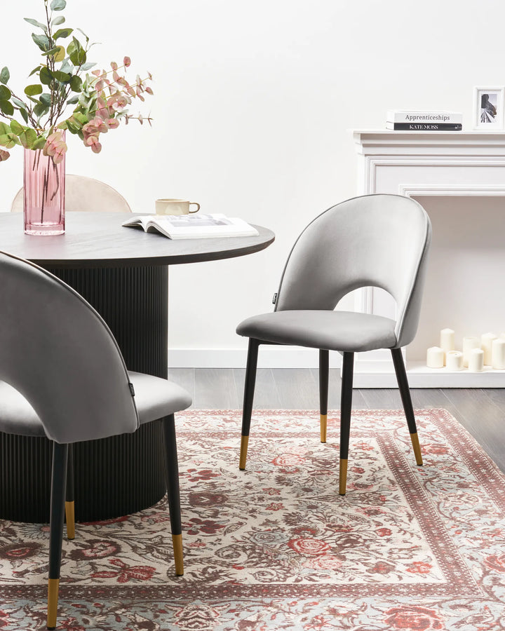 A pair of light grey velvet dining chairs styled around a contemporary dining table, creating a refined and sophisticated dining setting with soft neutral tones and luxurious details.