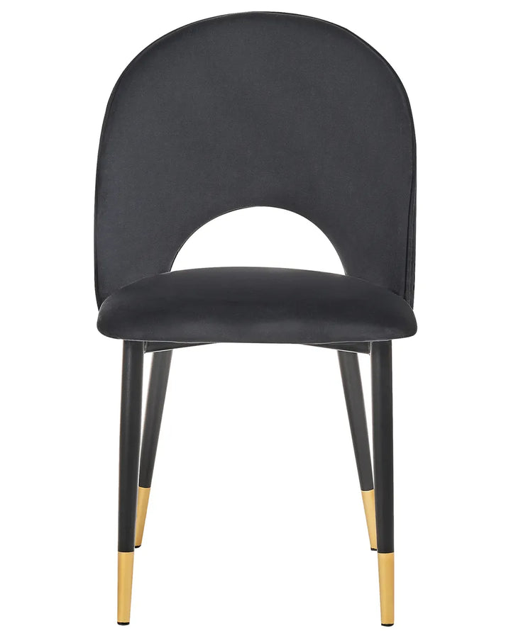 Black velvet dining chair with a distinctive curved backrest, cushioned seat, and black legs finished with elegant gold accents.