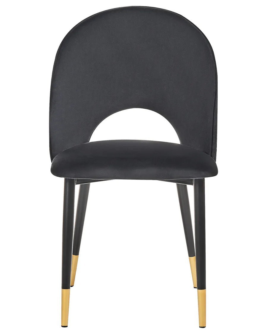 Black velvet dining chair with a distinctive curved backrest, cushioned seat, and black legs finished with elegant gold accents.