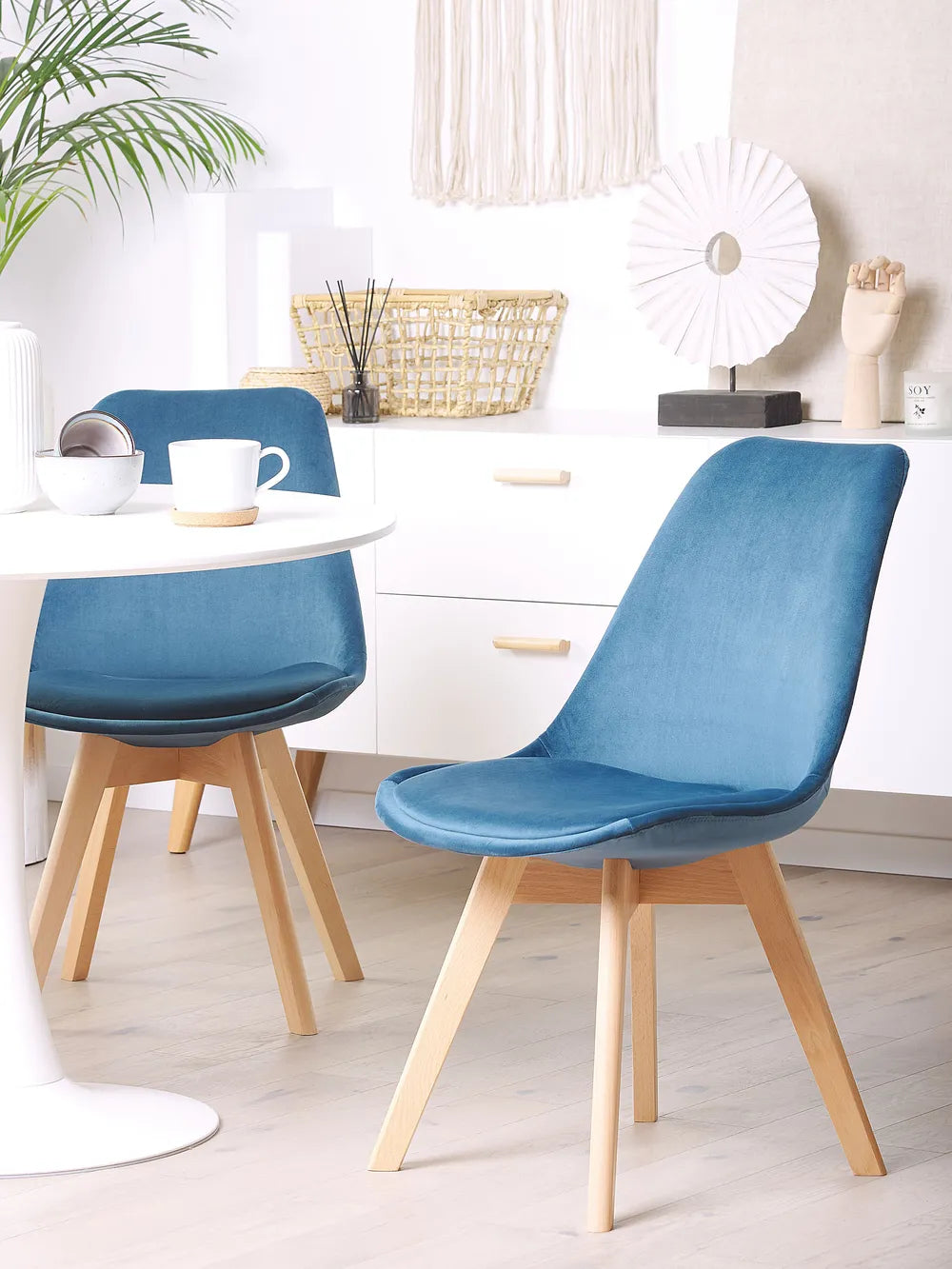 Bright, modern dining space showcasing blue velvet chairs paired with light wood accents for a fresh and inviting look.