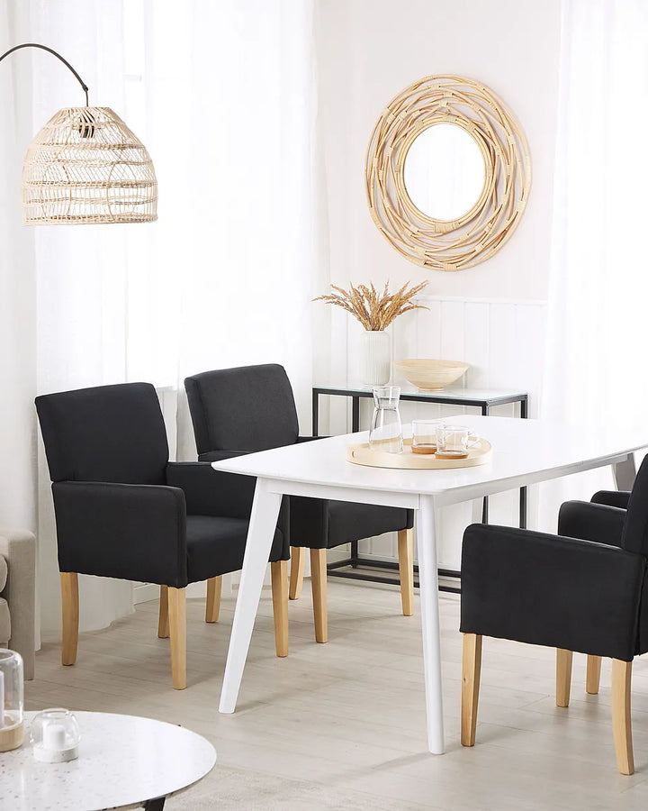 Black armchairs paired with a white dining table, creating a clean and modern dining space with Scandinavian-inspired charm.