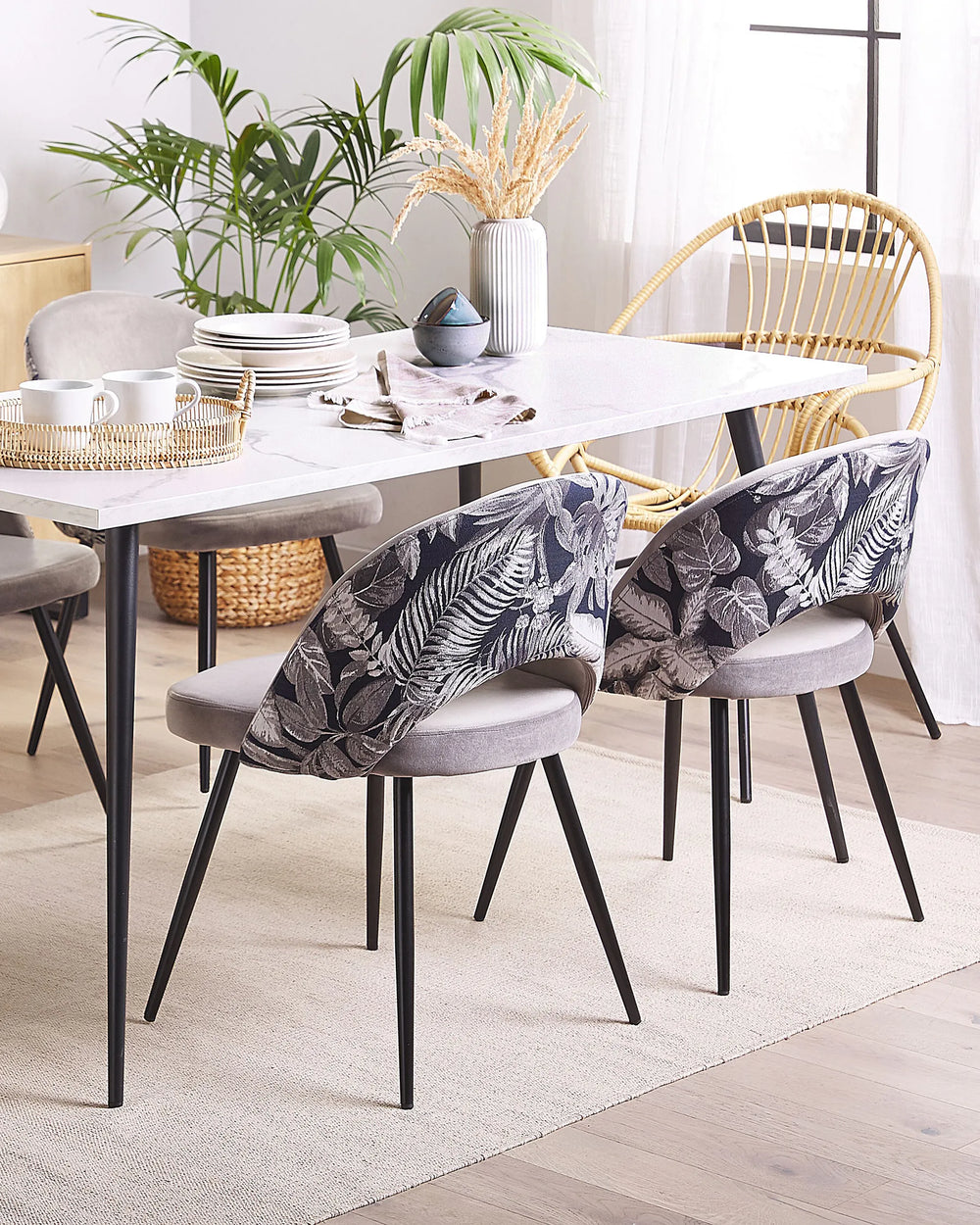 Grey velvet dining chairs with botanical print backs around a white dining table.