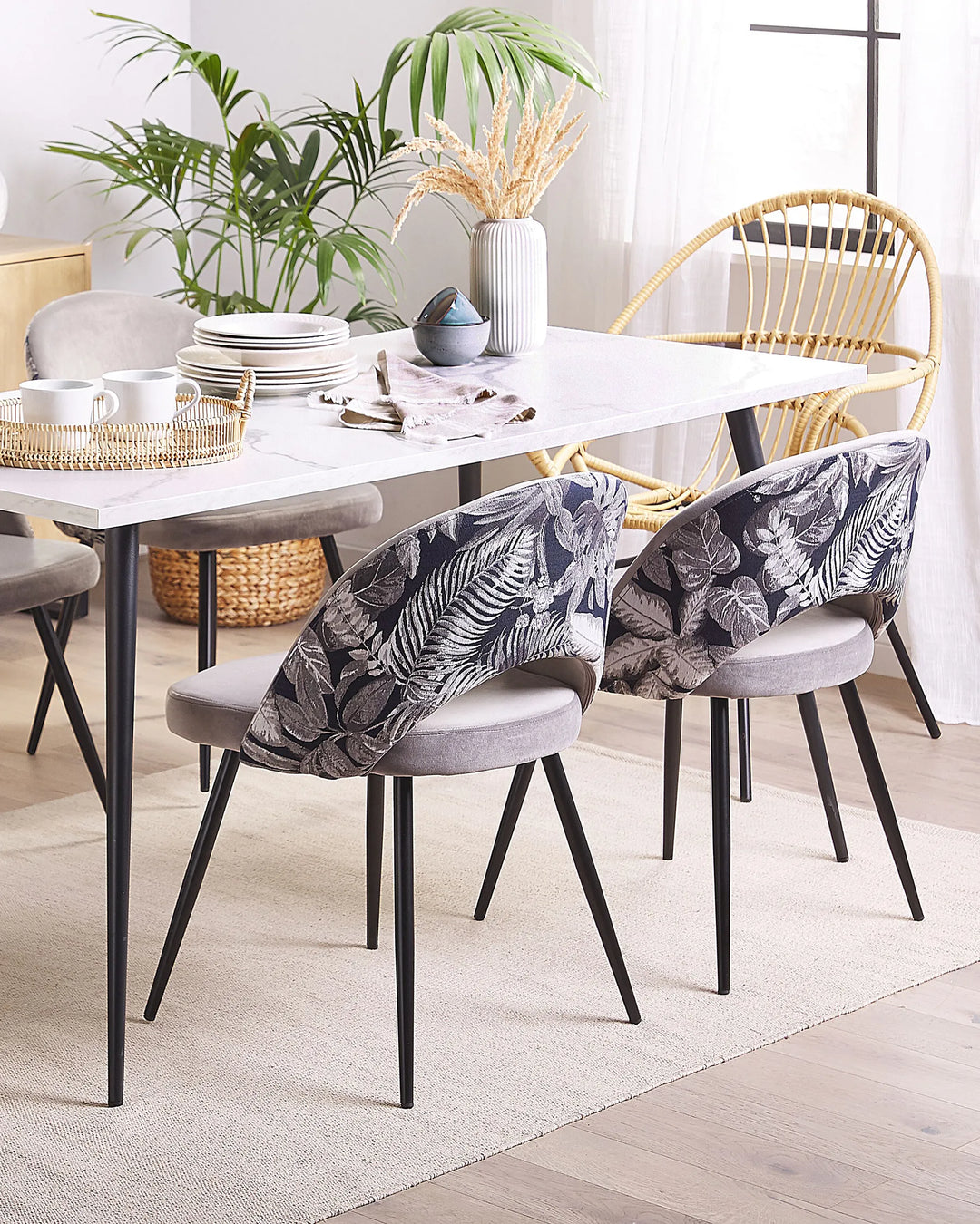 Grey velvet dining chairs with botanical print backs around a white dining table.