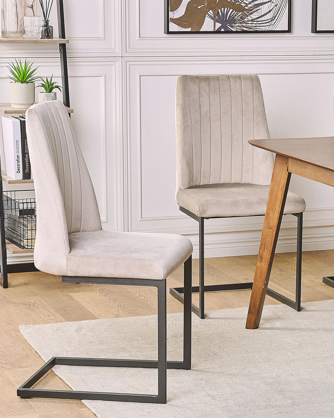 Contemporary dining setting showcasing beige velvet cantilever chairs paired with warm wood tones and black accents for a refined, modern look.