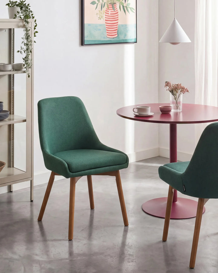 Modern green dining chairs styled around a round statement table, adding a fresh pop of colour and Scandinavian-inspired charm to a bright dining space.