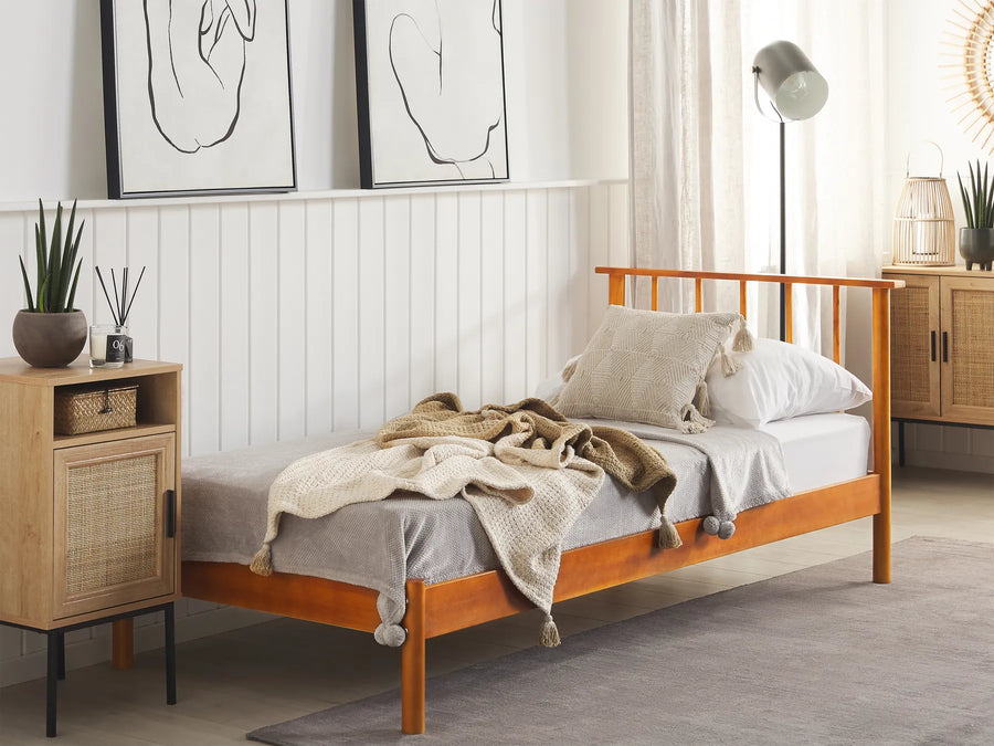 Wooden bed with bedding in a bedroom setting with a side table and decor.