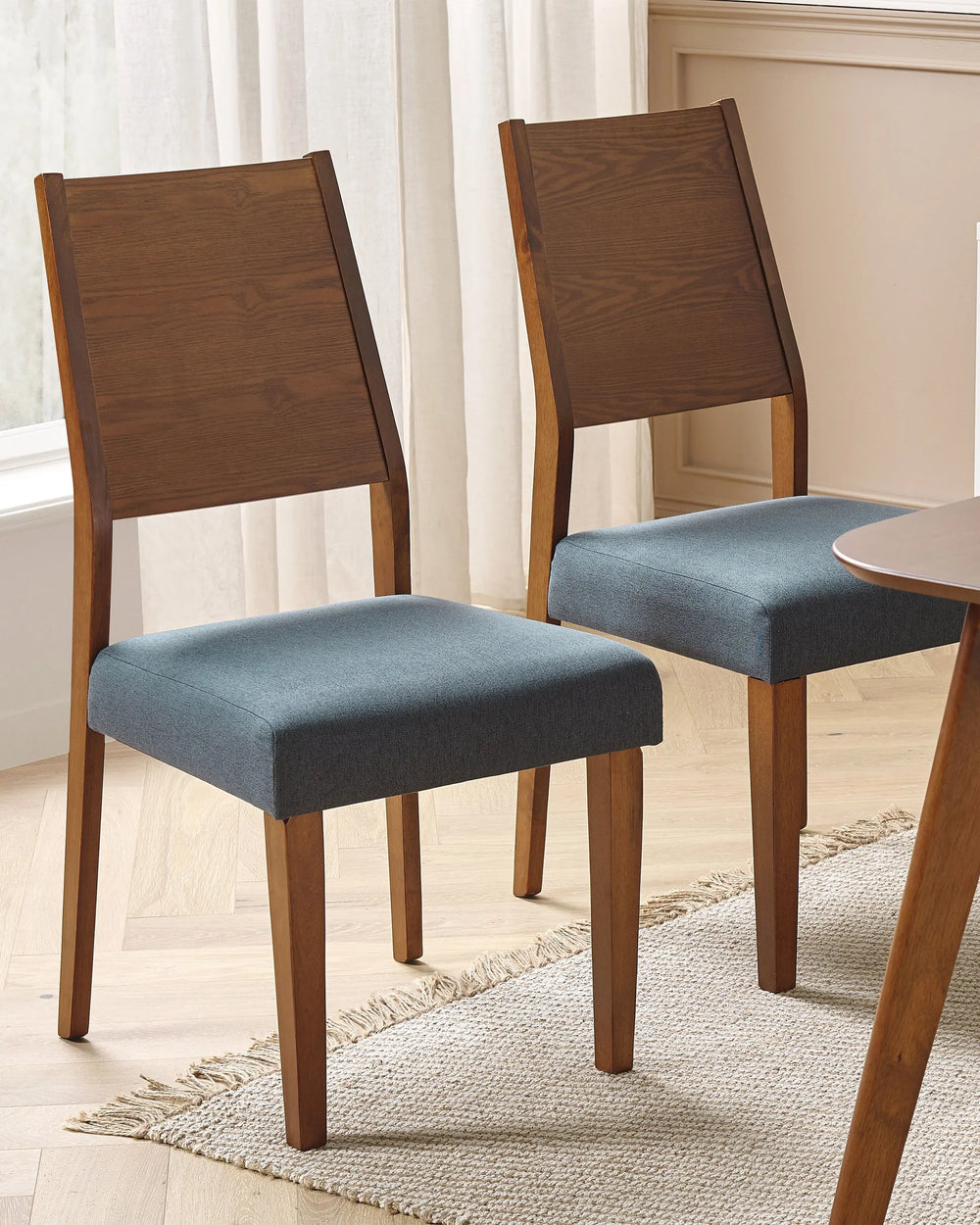 Arranged around a dining table, these chairs add warmth and sophistication to the space. The rich wood tones and blue fabric seats create a refined yet inviting dining setting.
