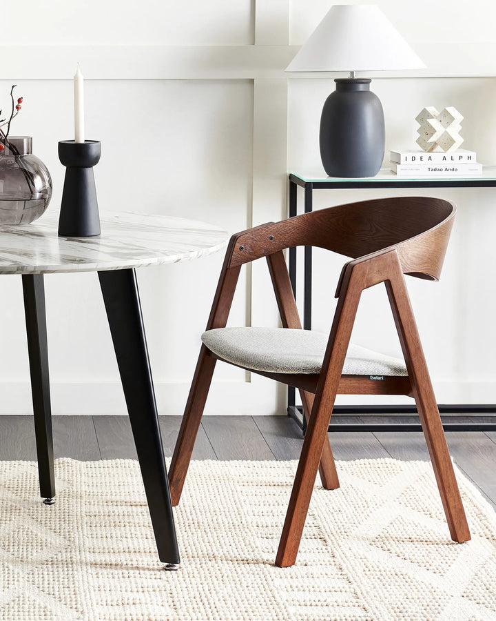 Dark wood dining chair with light grey upholstered seat beside a marble dining table in a modern dining room.