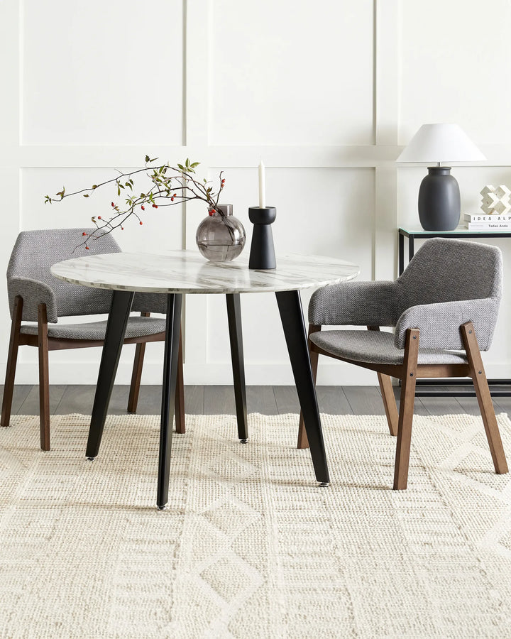 Grey armchairs with walnut frames around a round marble dining table in a bright, modern dining room with minimalist décor.