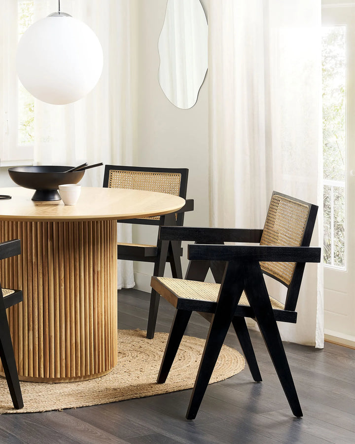 Wooden chair with woven rattan backrest and armrests in a modern indoor setting.