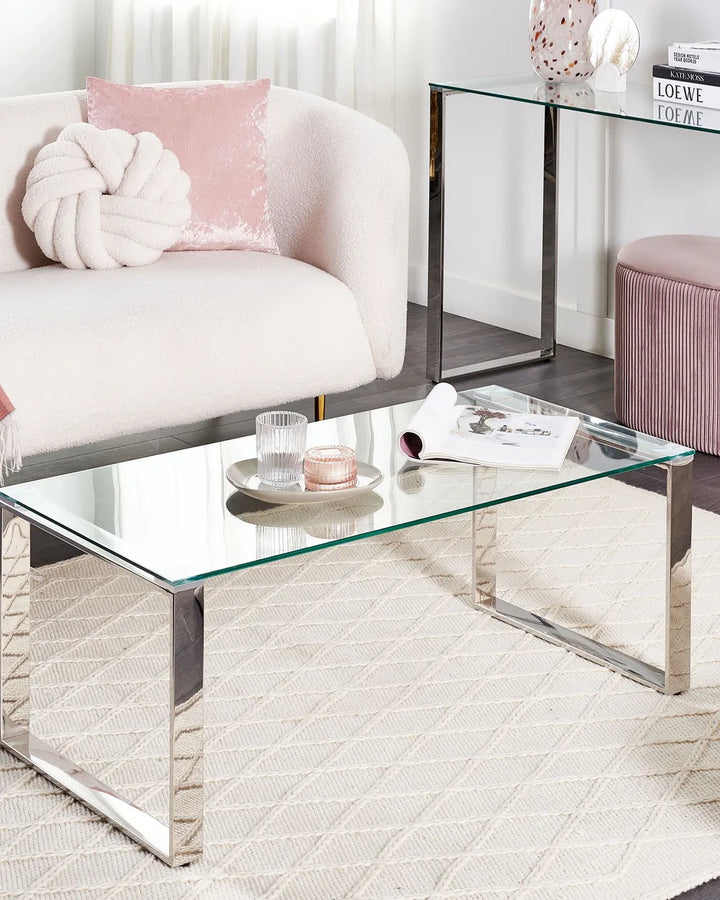 Modern living room with glass coffee table, white sofa, and pink accents.