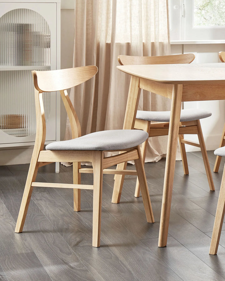 Light wood dining chairs with curved backrests and upholstered seats styled around a wooden dining table in a bright modern dining room.