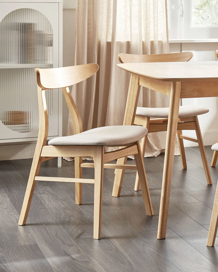 Light wood dining chairs with cream upholstered seats around a wooden dining table in a bright modern dining room.