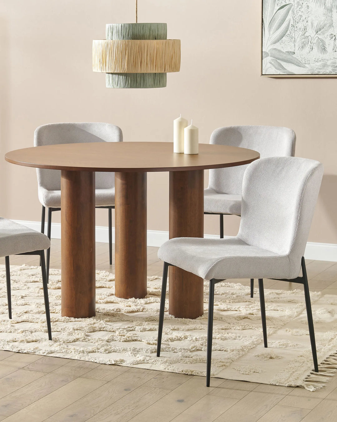 Modern dining setting showcasing light grey upholstered chairs paired with a round walnut-finish table. The neutral palette, sculptural pendant light, and textured rug create a warm, elegant atmosphere ideal for contemporary dining rooms.