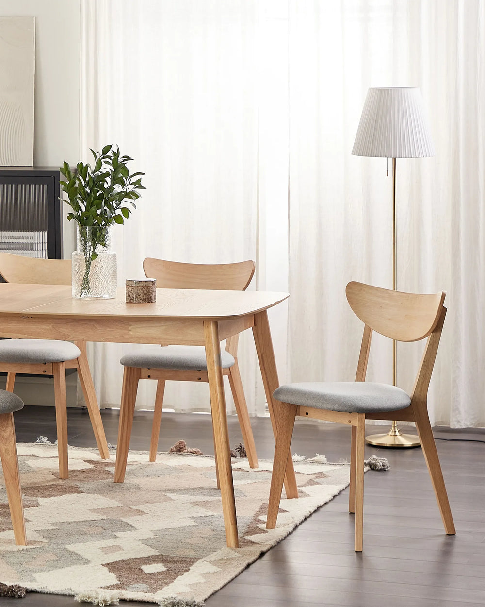 Light wood dining chairs with curved backrests and upholstered seats styled around a matching wooden dining table in a soft, modern dining room setting.