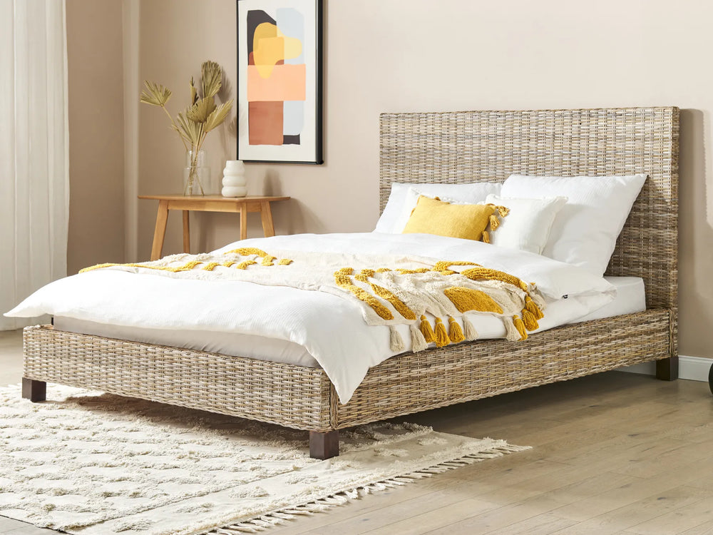 Wicker bed with white bedding and yellow accents in a bedroom setting.
