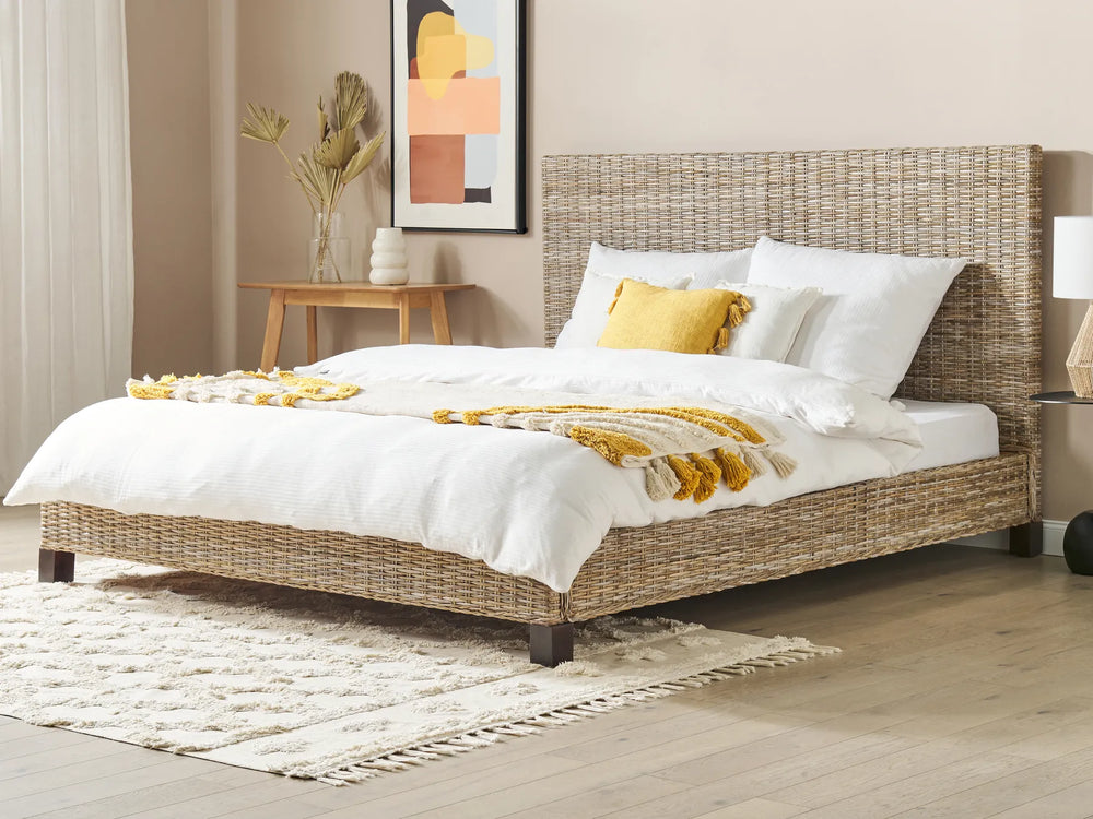 Wicker bed with white bedding and yellow pillows in a bedroom setting.