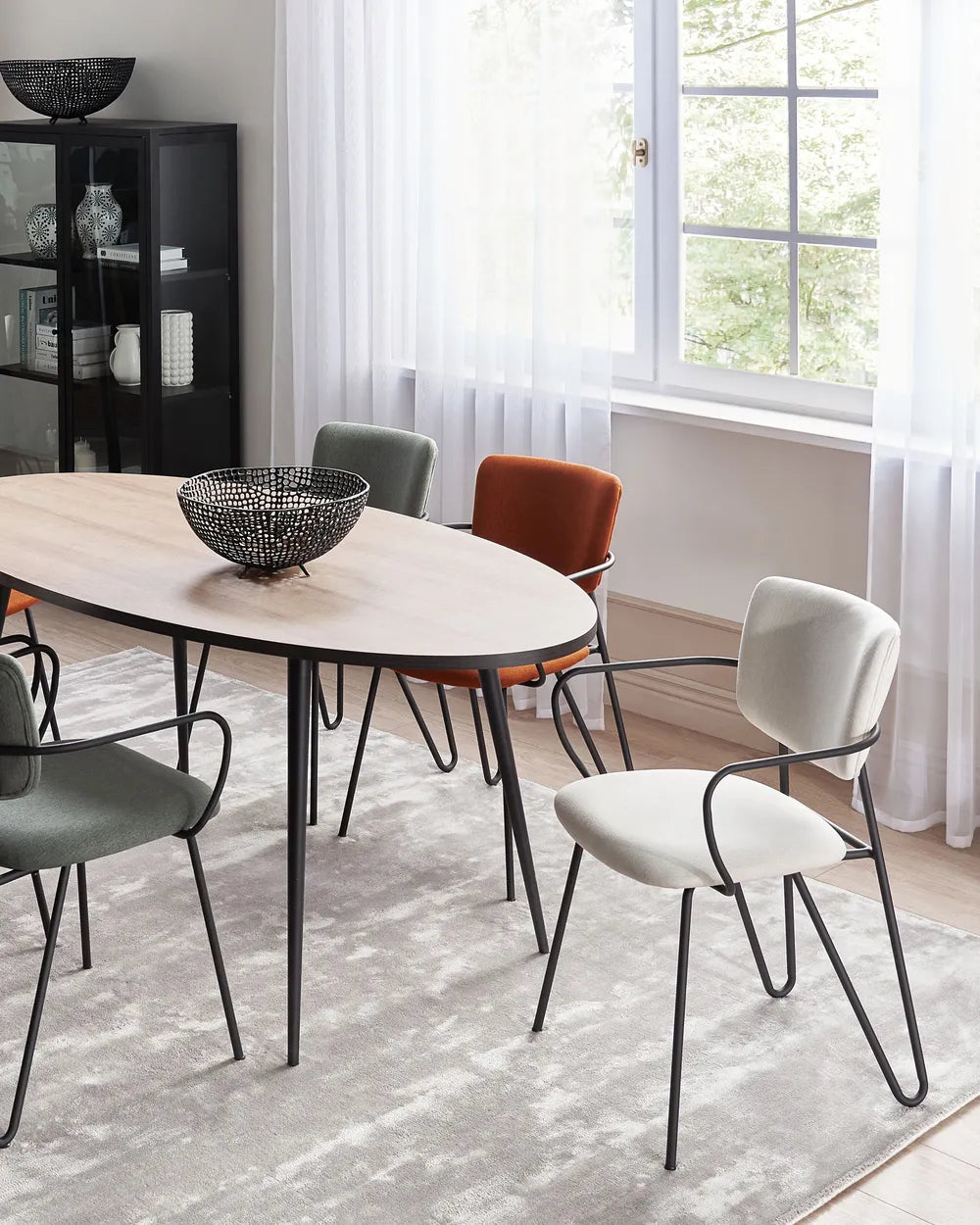 Modern dining room featuring cream accent chairs, a minimalist table, and sleek black metal details.