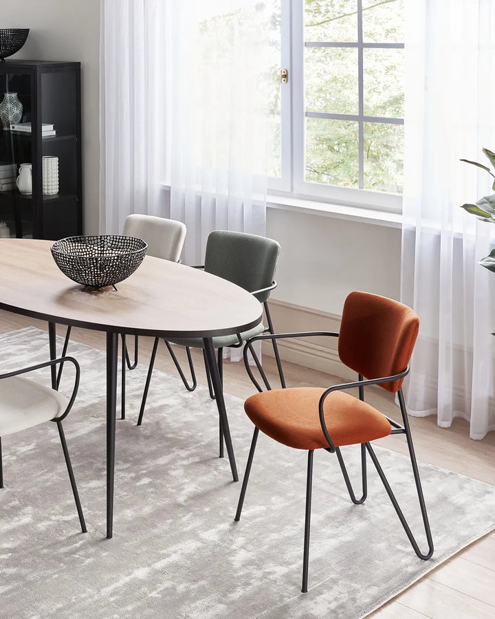 Contemporary dining space featuring vibrant orange accent chairs, a sleek dining table, and modern industrial details.