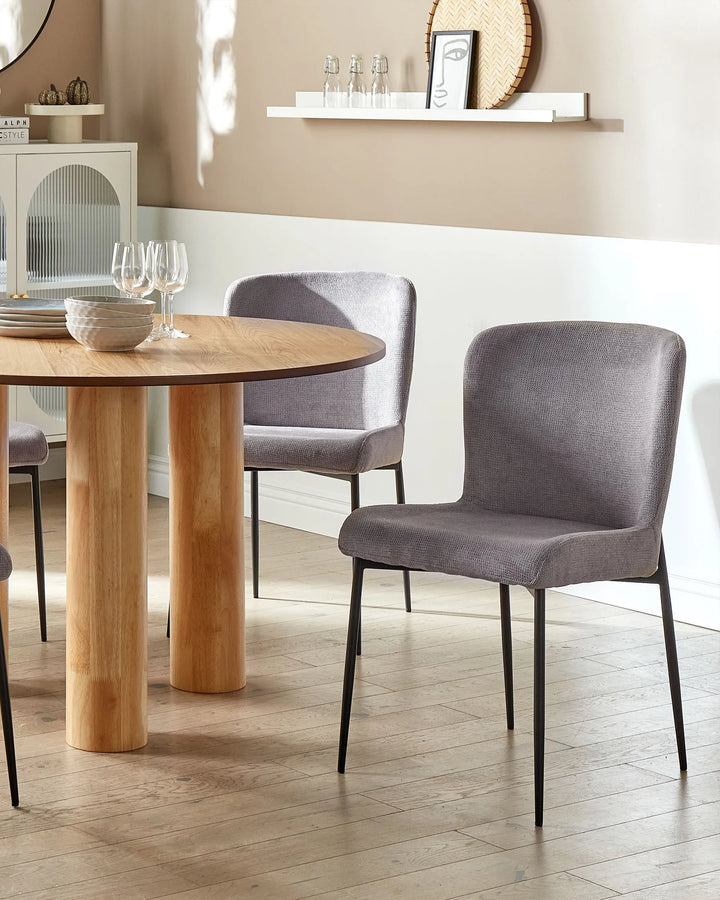 Grey dining chairs paired with a round wooden table in a bright, contemporary dining room.