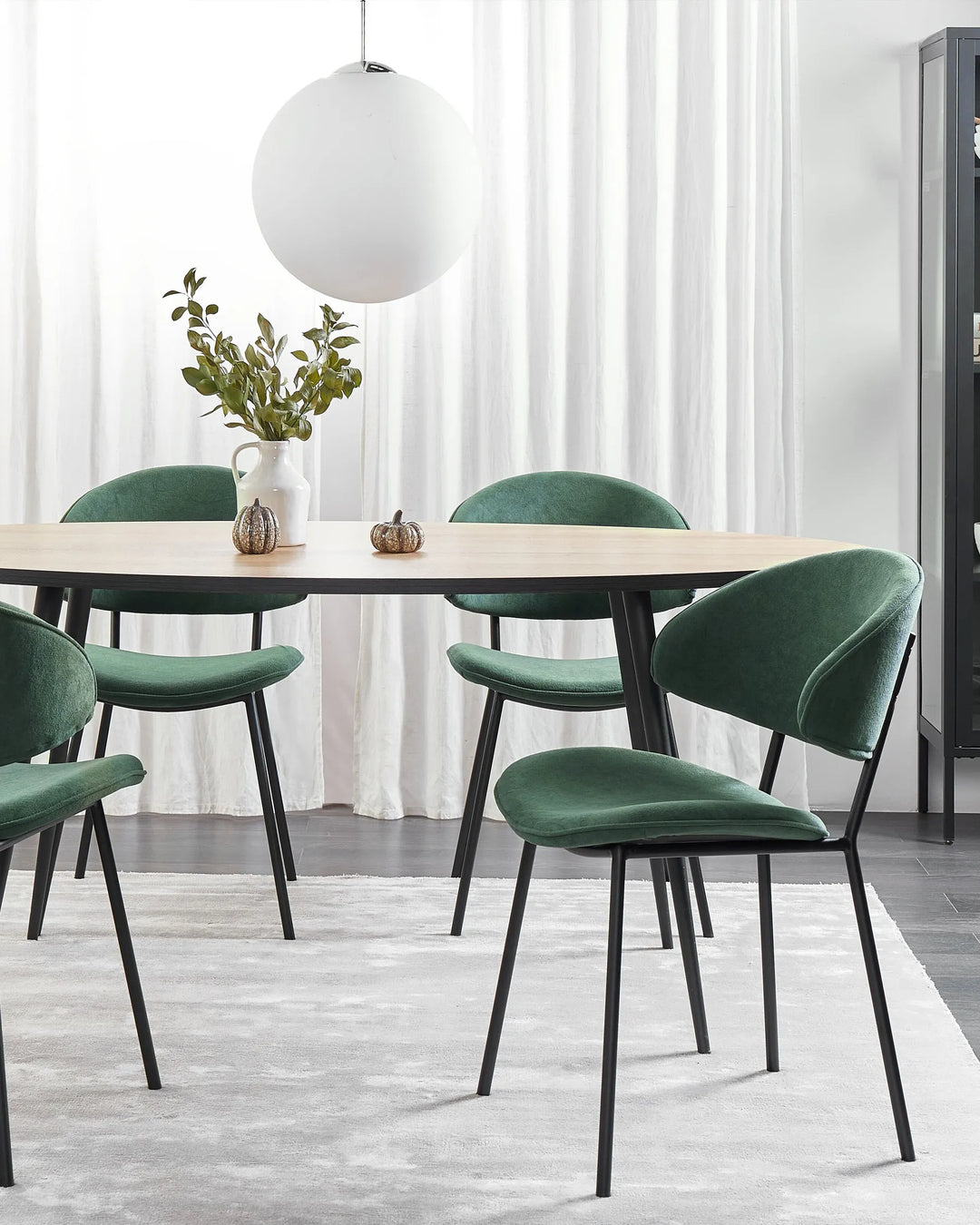 Modern dining area featuring the chair’s rich green upholstery, paired with a light wood table and minimalist décor for a fresh, elegant look.