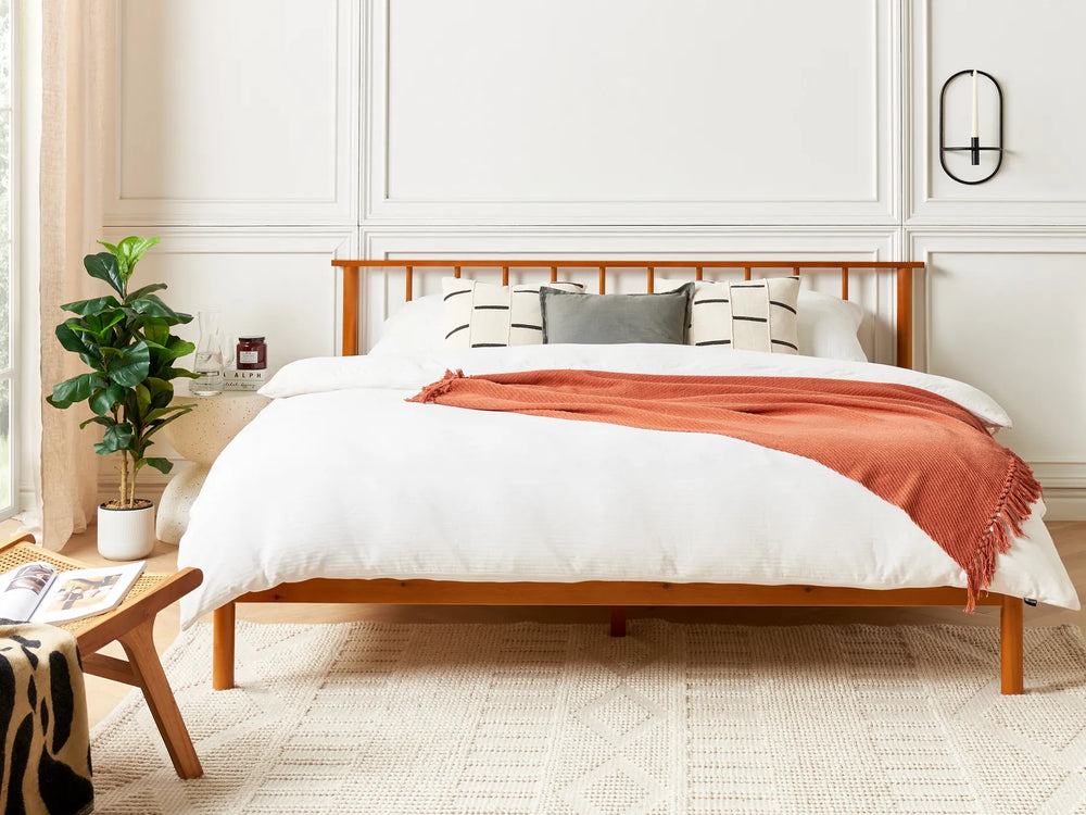 Bedroom with wooden bed frame, white bedding, and a red blanket.