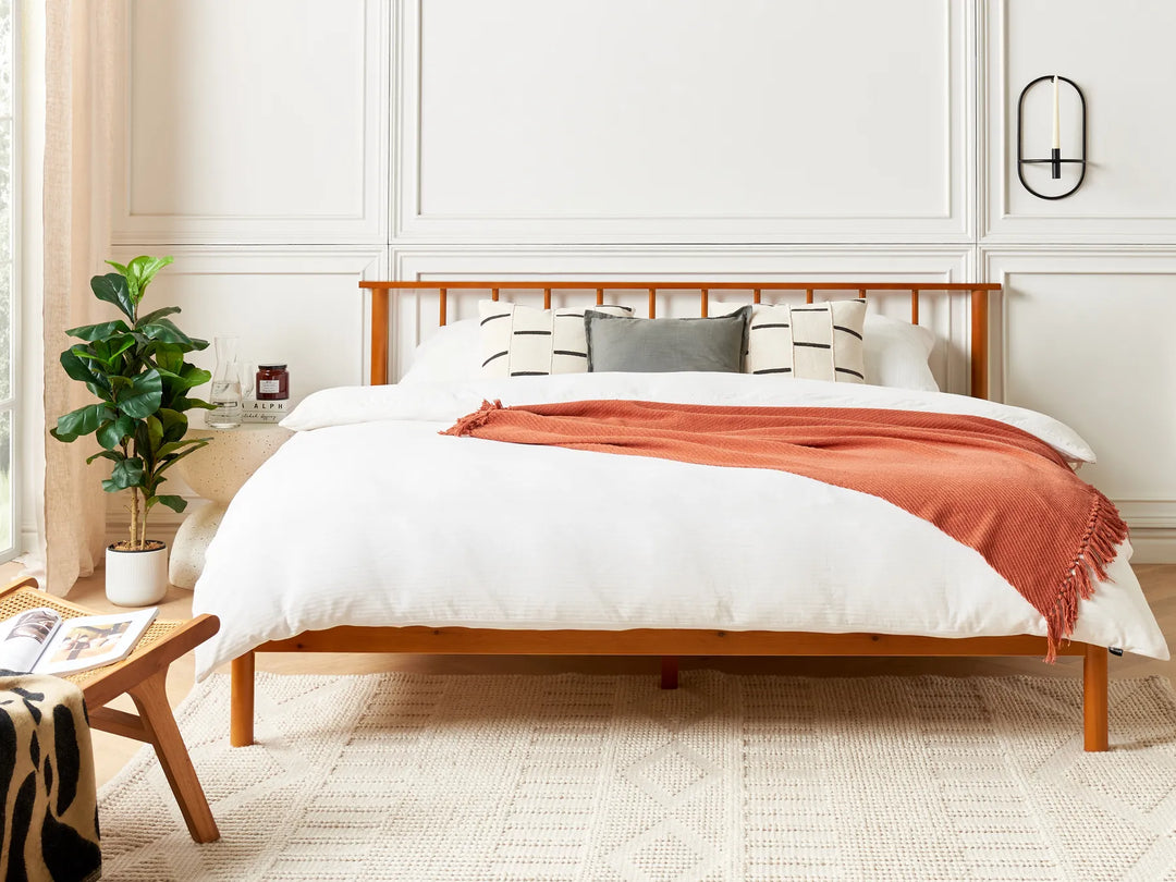 Bedroom with wooden bed frame, white bedding, and a red blanket.