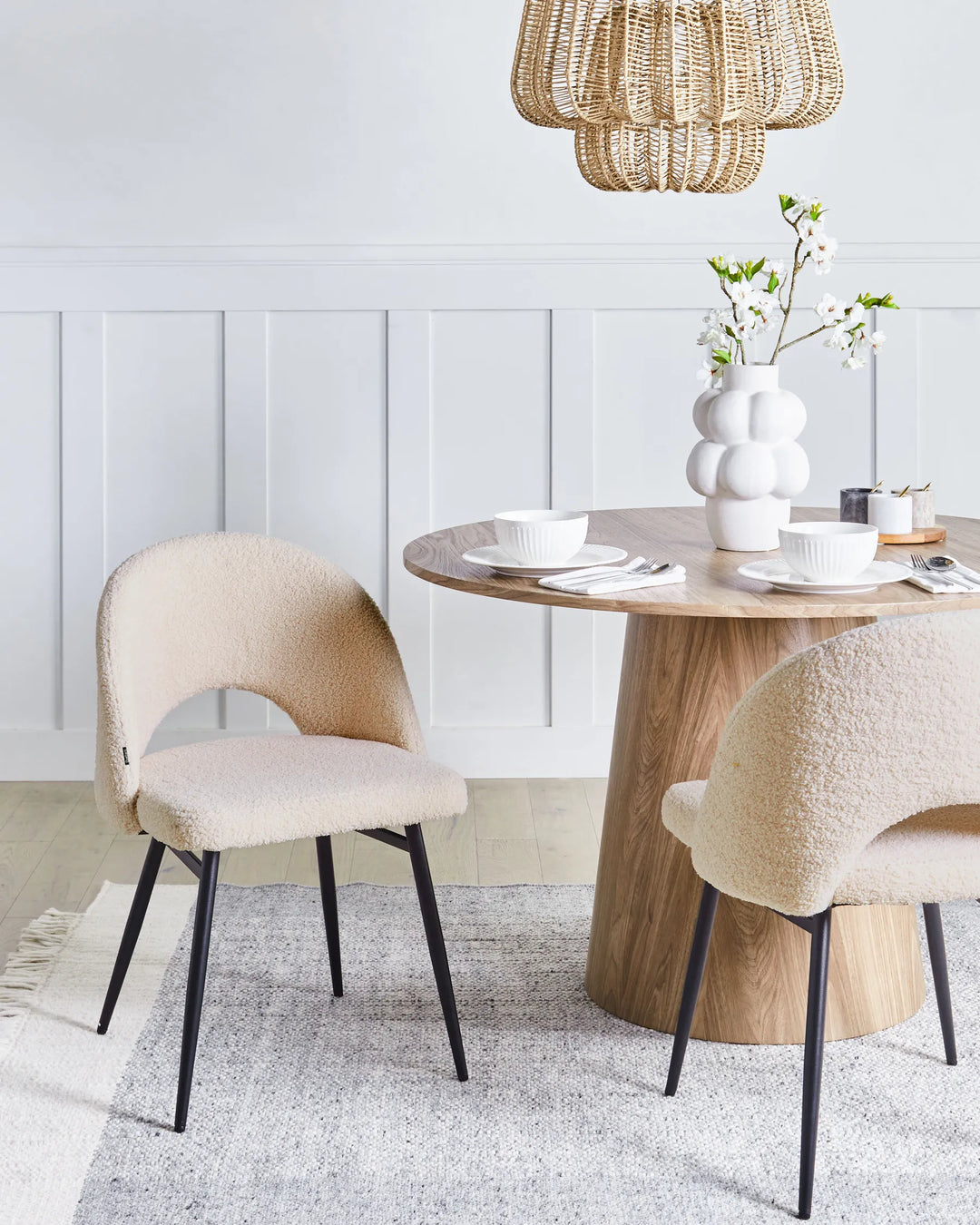 Cream bouclé dining chairs paired with a natural wood table in a bright, modern dining space.