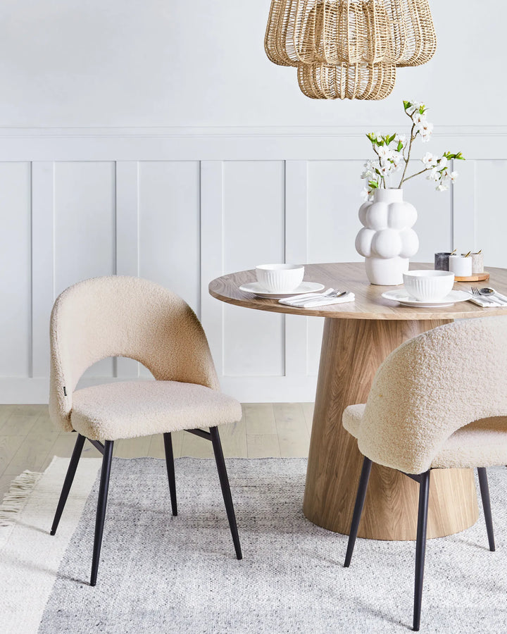 Cream bouclé dining chairs paired with a natural wood table in a bright, modern dining space.