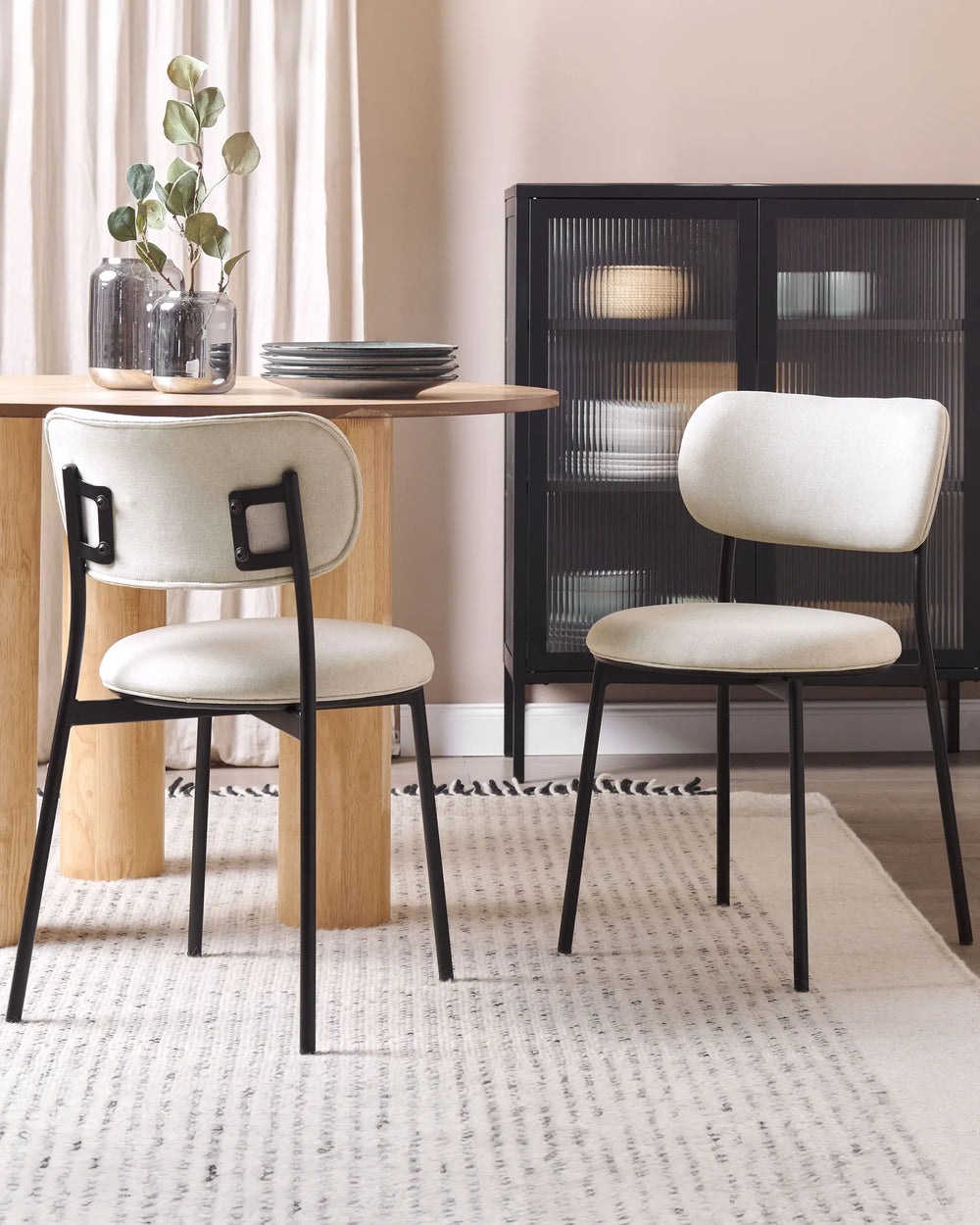 Modern dining setting featuring cream upholstered chairs paired with a natural wood table and black accents, creating a warm and sophisticated atmosphere.