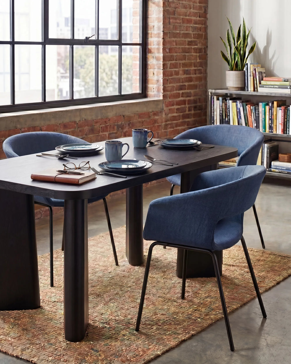 Dark blue fabric dining chairs with curved low backrests and black metal legs arranged around a dining table in a contemporary dining space with modern décor.
