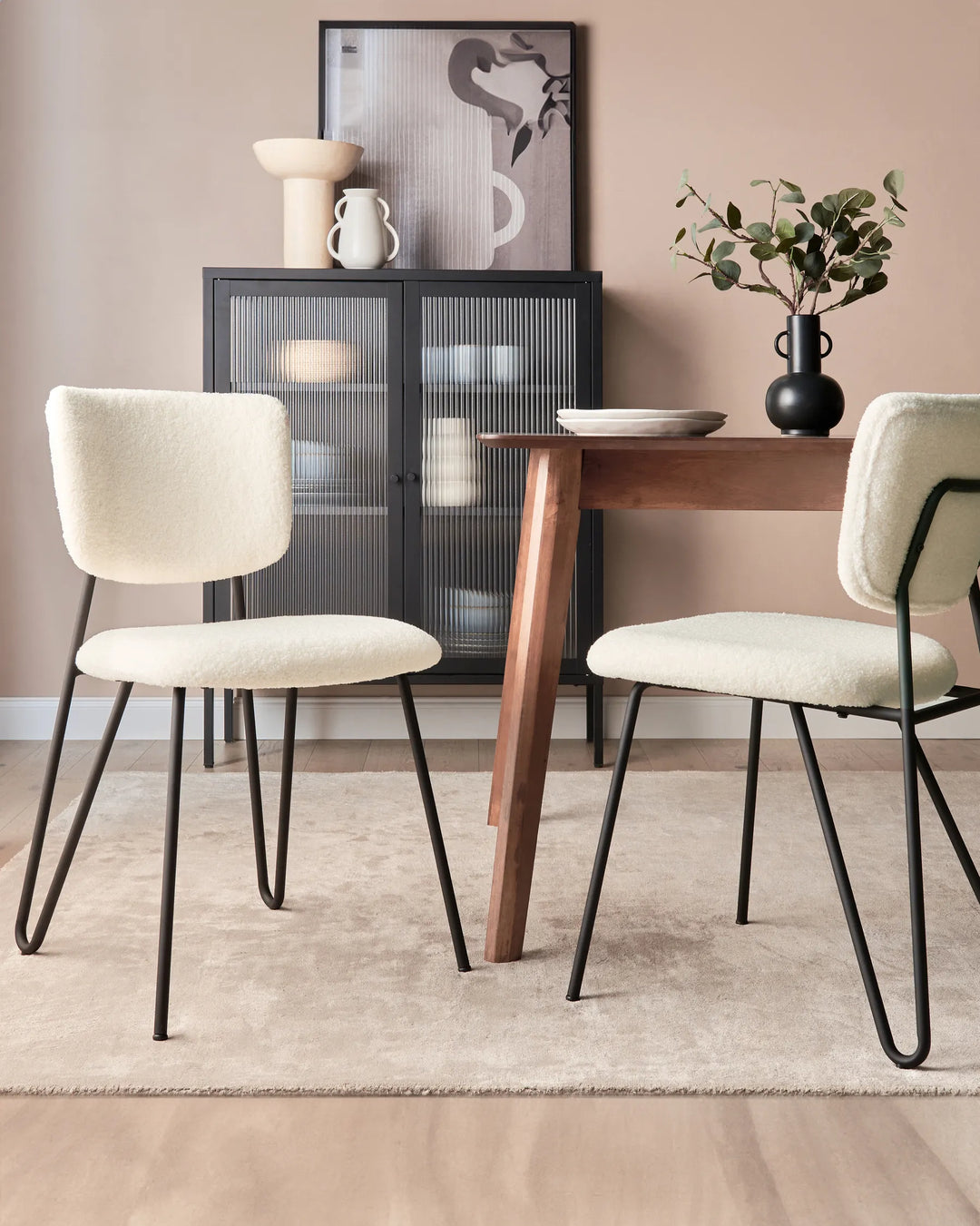 Modern dining setting featuring cozy cream bouclé chairs, a dark wood table, and contemporary black accents.