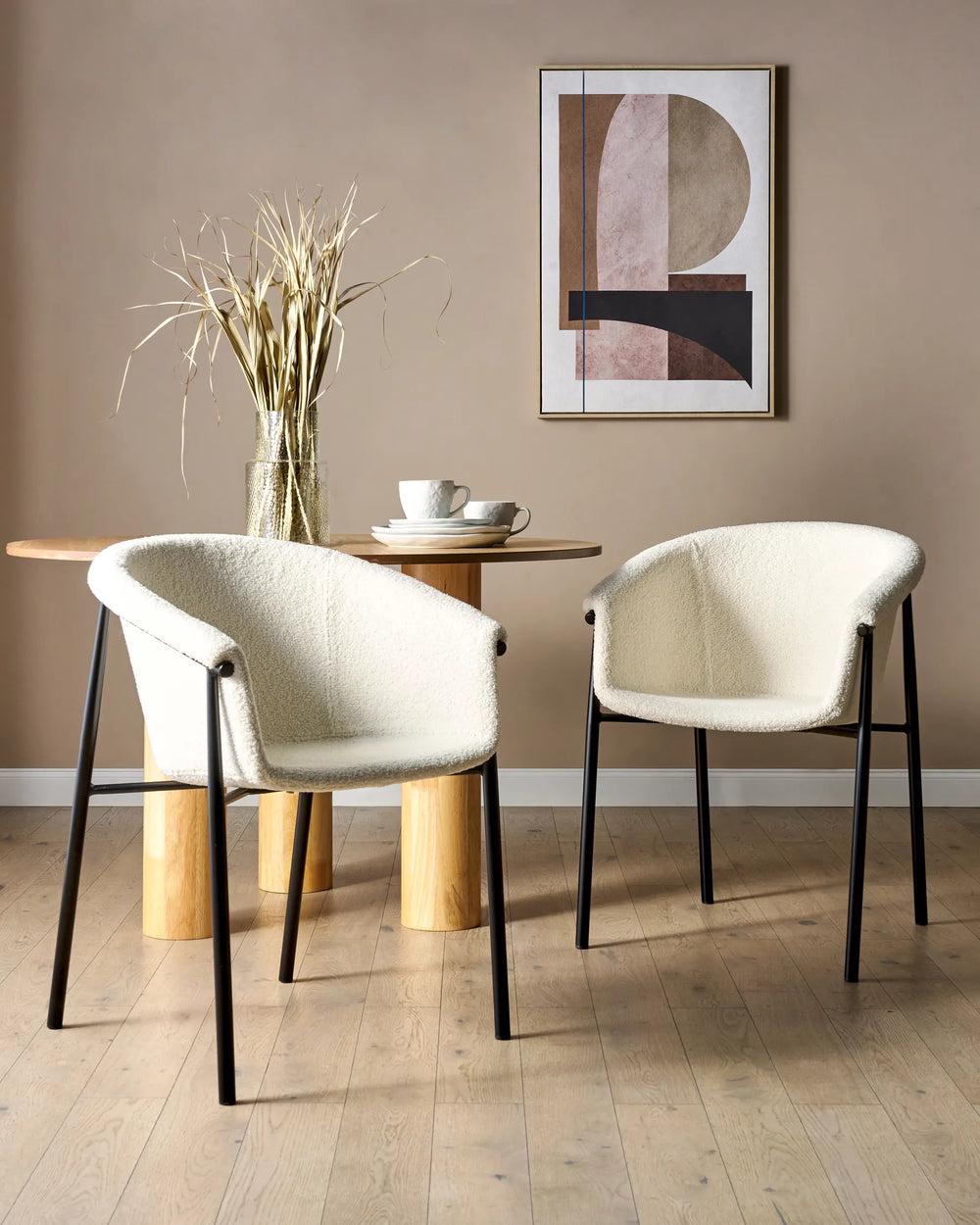 White bouclé dining chairs styled around a wood dining table in a warm, contemporary dining space.
