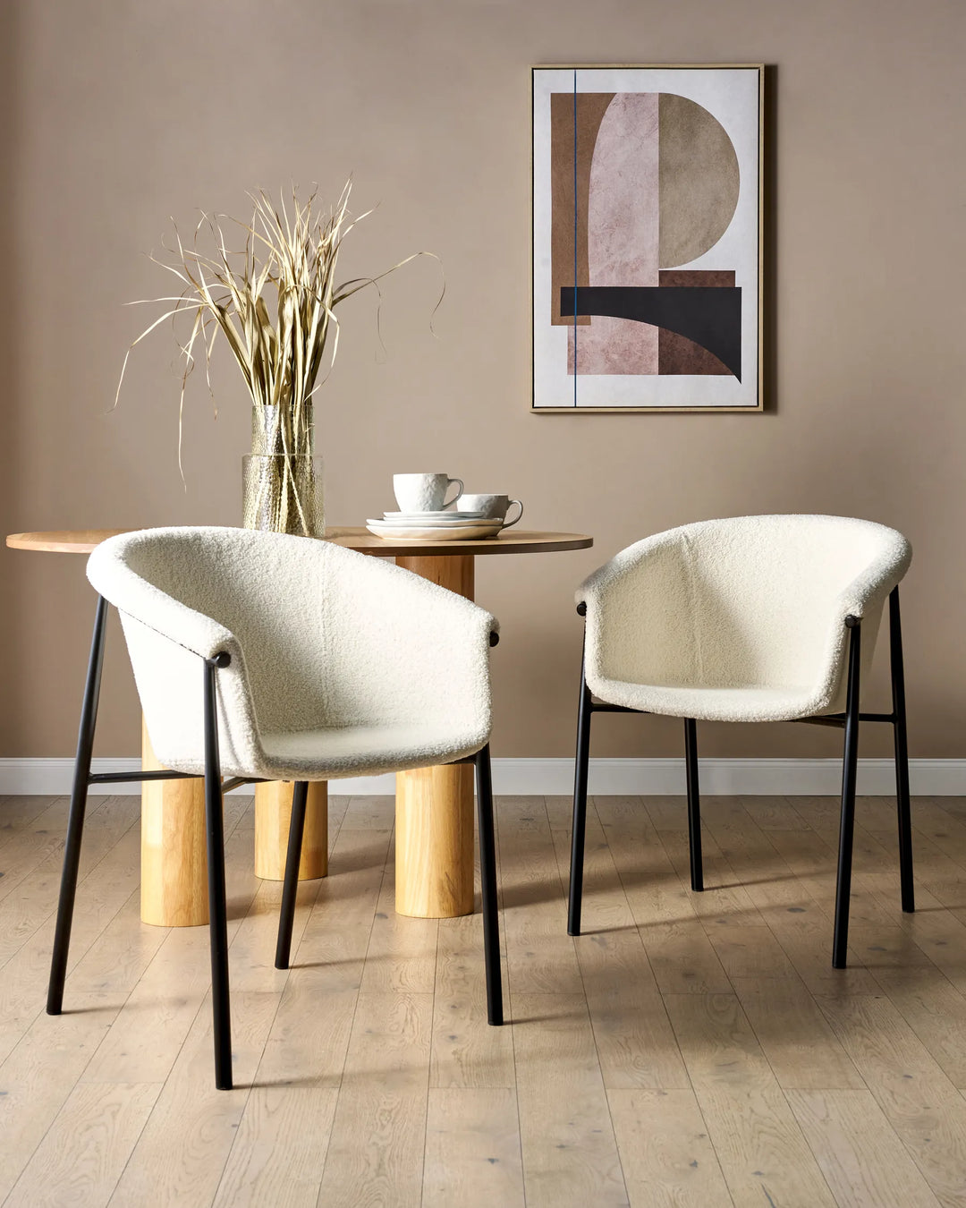 White bouclé dining chairs styled around a wood dining table in a warm, contemporary dining space.