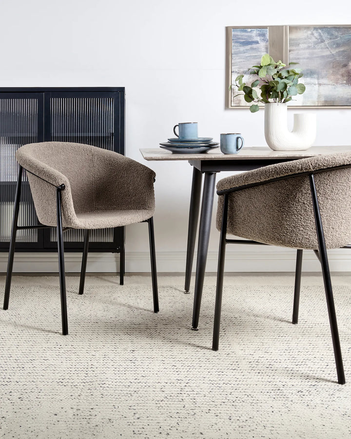 Taupe bouclé dining chairs styled around a modern dining table with soft neutral décor and black accents.