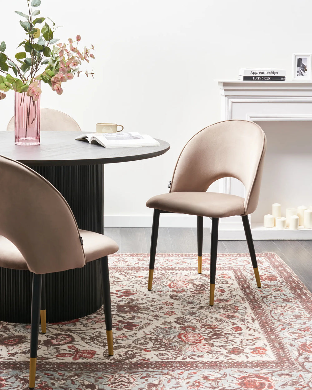 Taupe dining chairs styled around a black round table, adding a touch of elegance and warmth to a modern dining room.