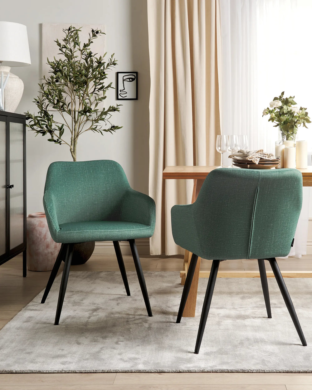 Dark green velvet dining chairs with rounded backrests and slanted black metal legs around a dining table in a contemporary dining space with modern décor.