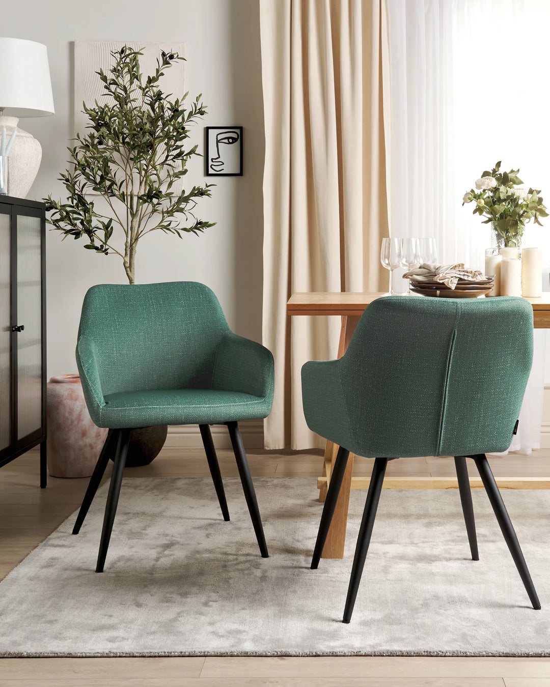 Dark green velvet dining chairs with rounded backrests and slanted black metal legs around a dining table in a contemporary dining space with modern décor.